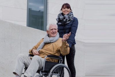 woman assisting the elderly man in wheelchair