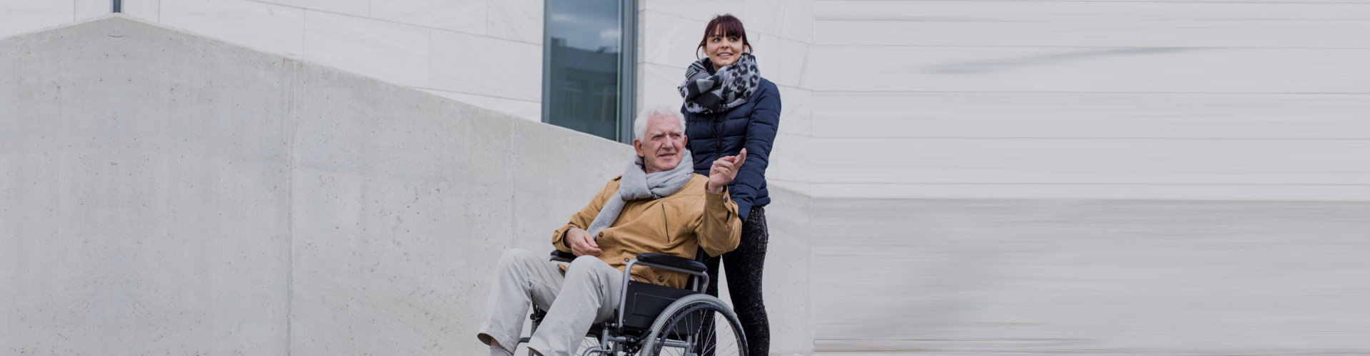 woman pushing senior man wheelchair outdoor